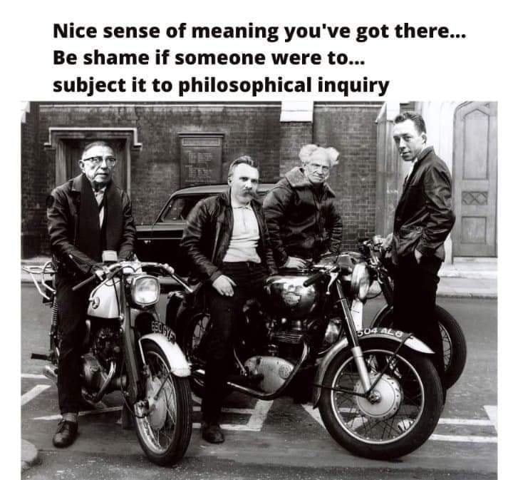 The meme is a black-and-white image of a group of men in suits and hats, likely from the 1960s, standing in front of a motorcycle. The image is captioned with a quote that is a play on the phrase "I don't know what you mean" from a 1960s British comedy series.