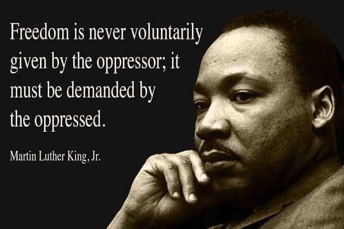 This meme features a famous quote from Martin Luther King Jr. in a bold, white font. The image is likely a photograph of Martin Luther King Jr. with a serious expression, and the quote is superimposed over it. The text reads: "Freedom is never voluntarily given by the oppressor; it must be demanded by the oppressed."