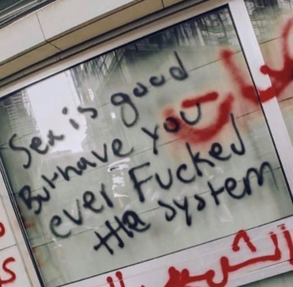 The meme is an image of a window with a handwritten note on it. The note reads: "Sex is good, but have you ever fucked the system?" The meme is likely humorous and ironic, implying that even in a situation where sex is enjoyable, the author is still aware of and critical of the societal norms and expectations that can be oppressive or limiting.