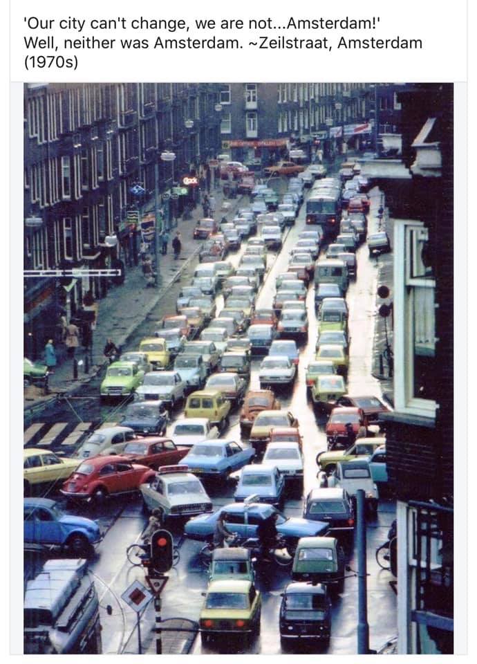 The meme is a photo of a busy Amsterdam street from the 1970s, with a sea of old cars and bicycles. The image is captioned with a quote from a 1970s Amsterdam resident, saying "In Amsterdam, they asked me what I wanted to do with my life. I told them I wanted to be a street musician. They told me to see a job counselor."