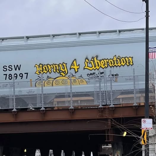 The meme is a photo of a train car with a graffiti message on it. The message reads "Horny 4 Liberation" in a playful, cursive font. The image is likely a humorous take on the idea of a train car being a symbol of freedom or liberation, with the added twist of "horny" implying a more... risqué interpretation.